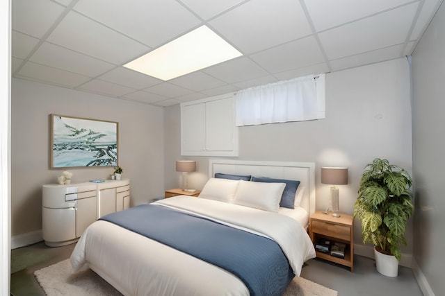 bedroom with a paneled ceiling and concrete floors