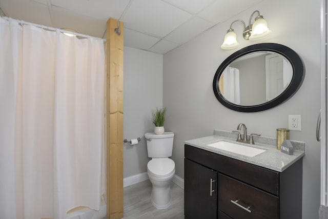 bathroom with a drop ceiling, vanity, hardwood / wood-style floors, and toilet