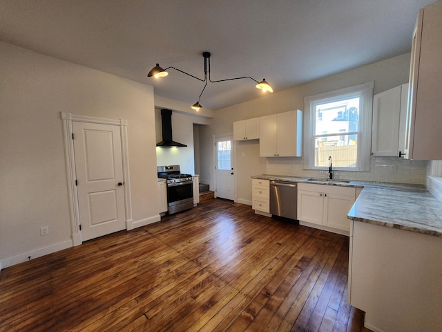 kitchen with appliances with stainless steel finishes, wall chimney exhaust hood, dark wood-type flooring, sink, and white cabinetry