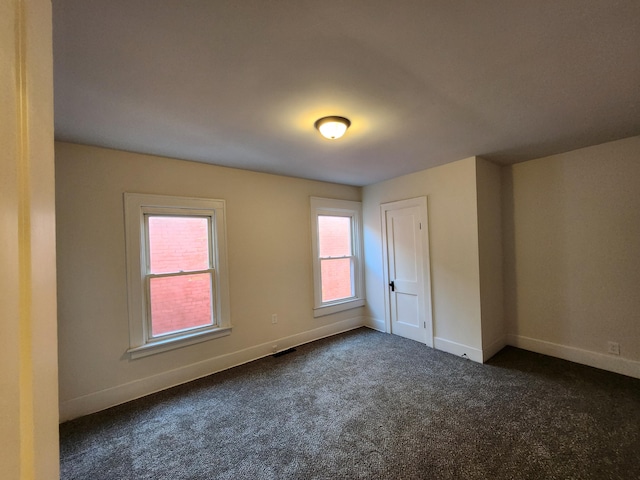 unfurnished room featuring dark carpet