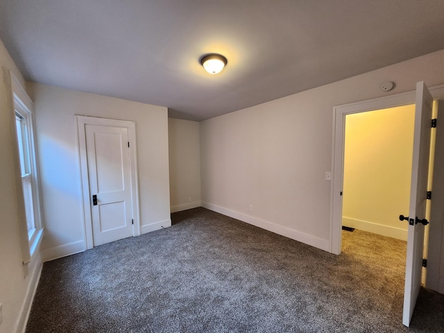 unfurnished bedroom with dark colored carpet and a closet