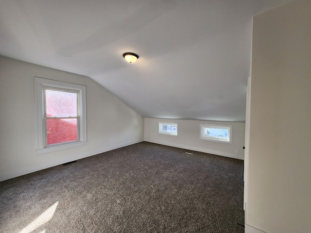 additional living space with dark colored carpet and lofted ceiling