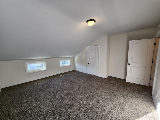 bonus room with dark carpet and lofted ceiling