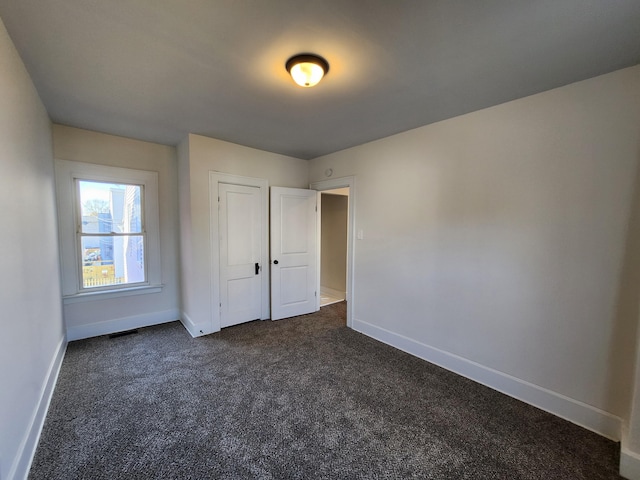 unfurnished bedroom featuring dark colored carpet and a closet