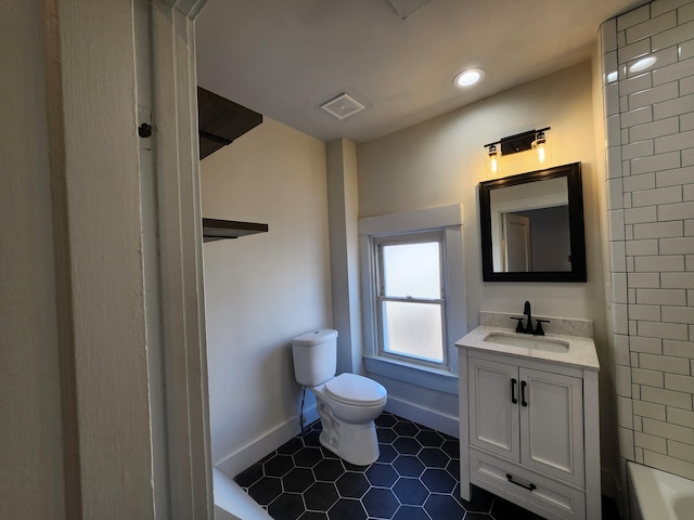 bathroom featuring tile patterned floors, a bathing tub, vanity, and toilet