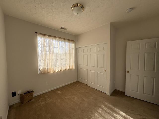 unfurnished bedroom featuring a closet, carpet floors, and a textured ceiling