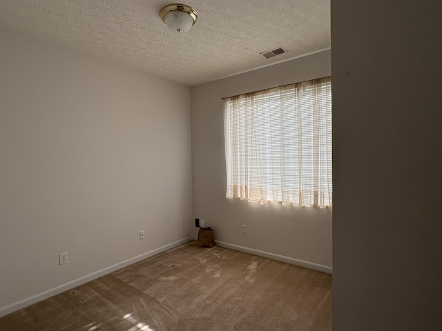 carpeted spare room with a textured ceiling