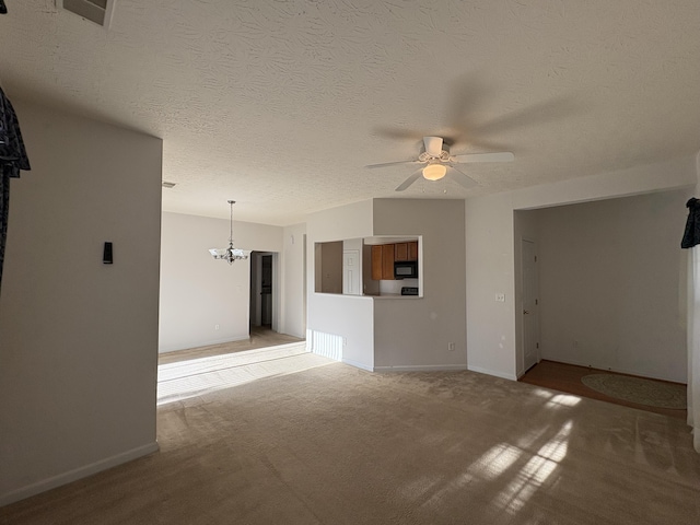 empty room with a textured ceiling, carpet floors, and ceiling fan with notable chandelier