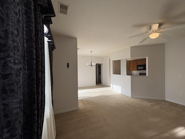 spare room with light carpet, a textured ceiling, and ceiling fan with notable chandelier