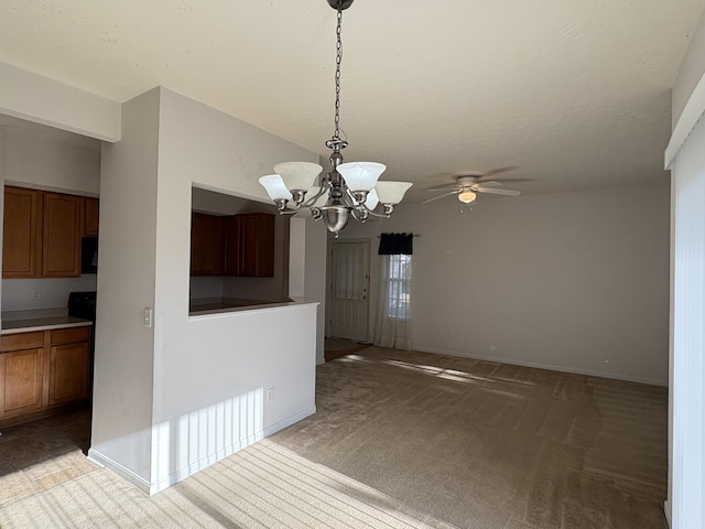 unfurnished dining area featuring a textured ceiling, ceiling fan with notable chandelier, and light colored carpet