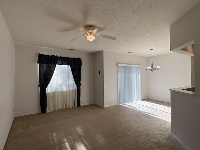 unfurnished room with carpet flooring, a textured ceiling, and ceiling fan with notable chandelier