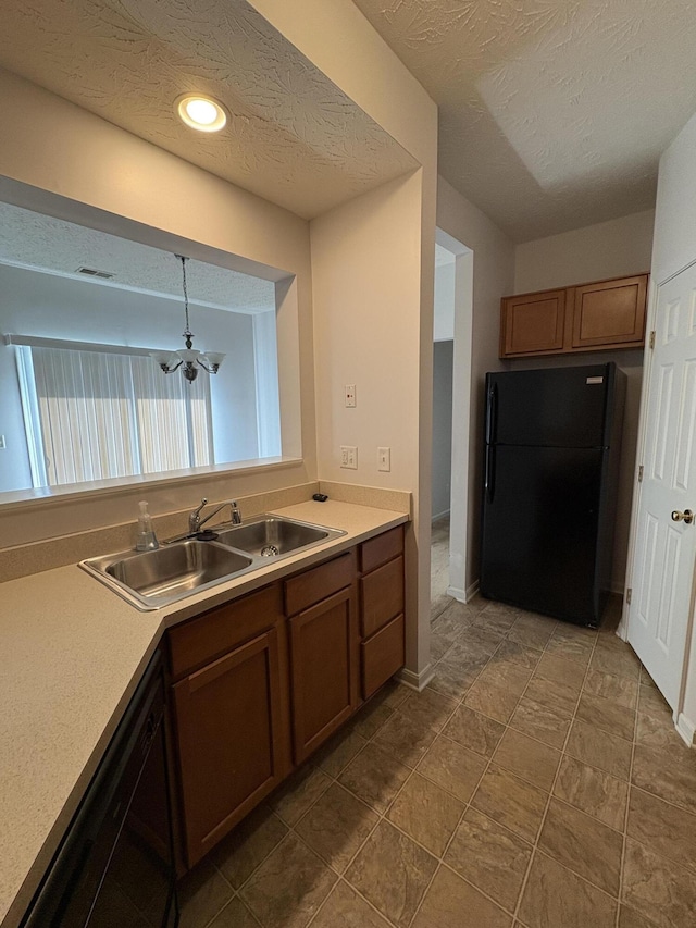 kitchen featuring black appliances, tile patterned floors, sink, hanging light fixtures, and a textured ceiling