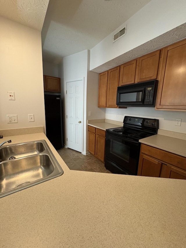 kitchen featuring sink, black appliances, and a textured ceiling