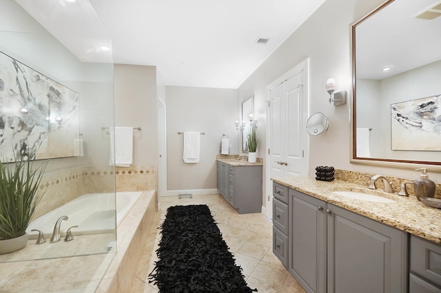 bathroom with tiled bath, tile patterned flooring, and vanity