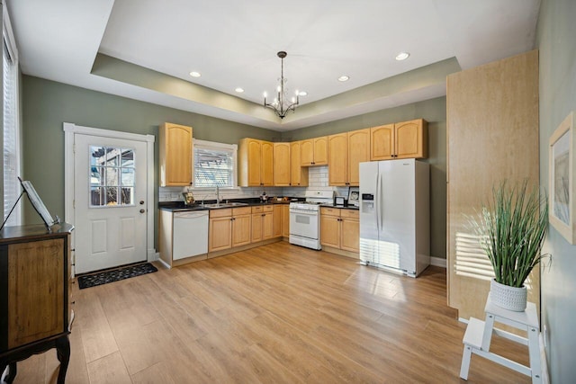 kitchen featuring sink, a notable chandelier, pendant lighting, white appliances, and light wood-type flooring