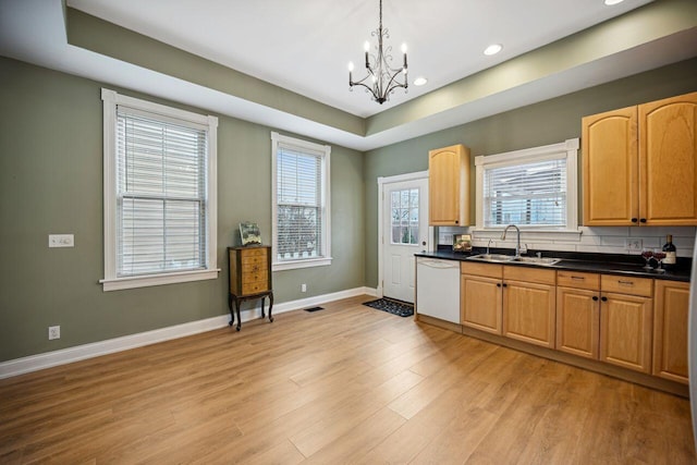 kitchen with sink, white dishwasher, a chandelier, pendant lighting, and light hardwood / wood-style floors