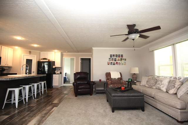 living room featuring ornamental molding, dark wood-type flooring, ceiling fan, and a textured ceiling