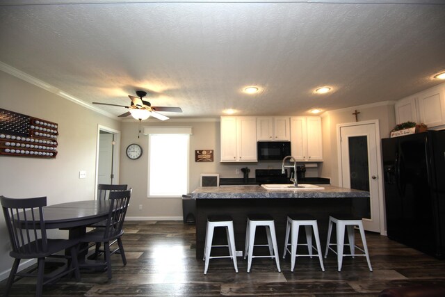 kitchen featuring a kitchen island with sink, sink, white cabinets, and black appliances