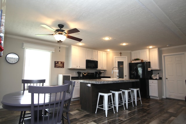 kitchen with sink, a breakfast bar area, black appliances, and white cabinets