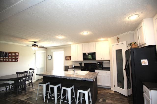 kitchen with sink, white cabinetry, dark hardwood / wood-style floors, black appliances, and an island with sink