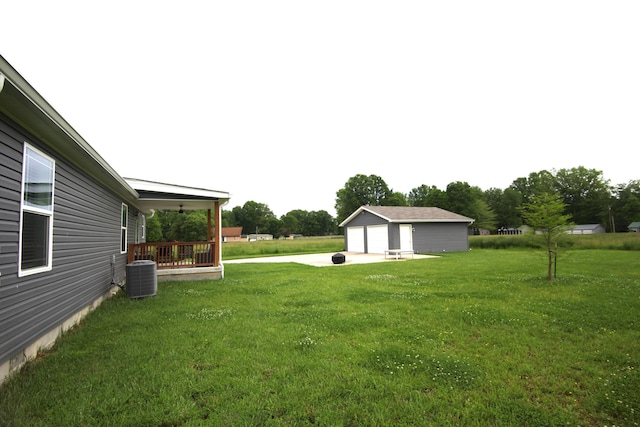 view of yard with a garage, an outdoor structure, and central AC