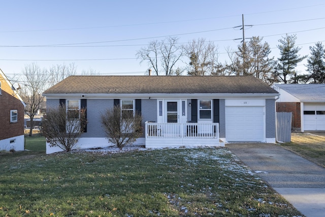 ranch-style home featuring covered porch, a front yard, and a garage