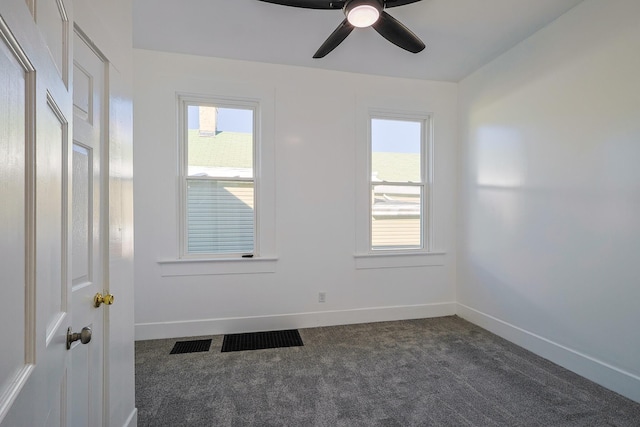 unfurnished room featuring ceiling fan, plenty of natural light, and dark colored carpet