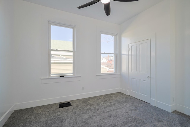 spare room featuring ceiling fan, carpet floors, and a wealth of natural light