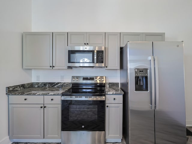 kitchen featuring gray cabinets, appliances with stainless steel finishes, and dark stone counters