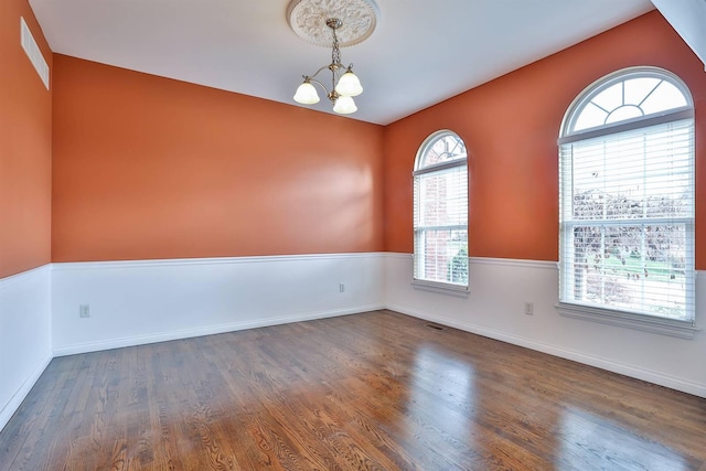 empty room featuring a chandelier and dark hardwood / wood-style flooring