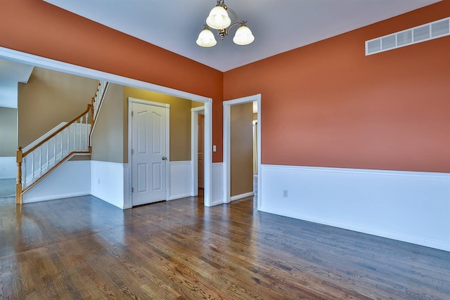 empty room with dark hardwood / wood-style floors and an inviting chandelier