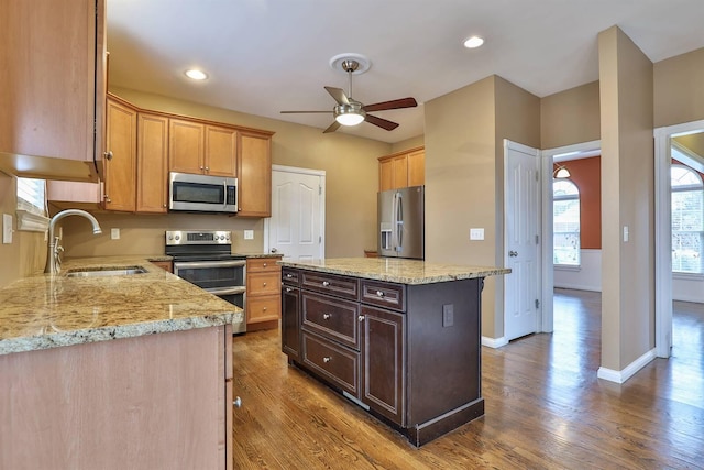 kitchen featuring hardwood / wood-style floors, a kitchen island, sink, and appliances with stainless steel finishes