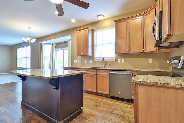 kitchen with sink, pendant lighting, a breakfast bar area, appliances with stainless steel finishes, and light wood-type flooring