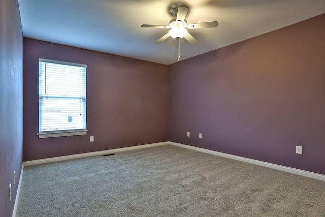 unfurnished room with ceiling fan and carpet