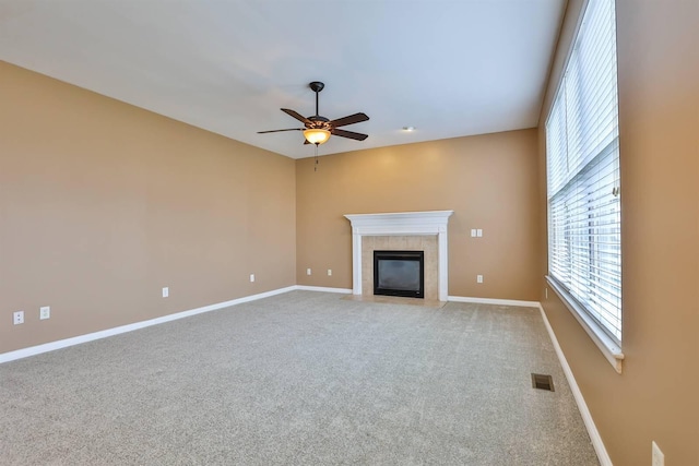 unfurnished living room with ceiling fan, light colored carpet, and a tile fireplace