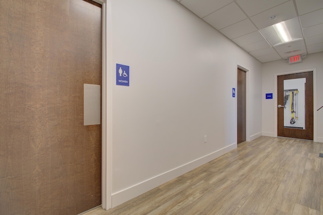 hallway with light hardwood / wood-style flooring and a drop ceiling