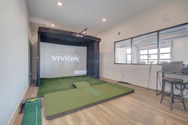 game room with wood-type flooring and golf simulator