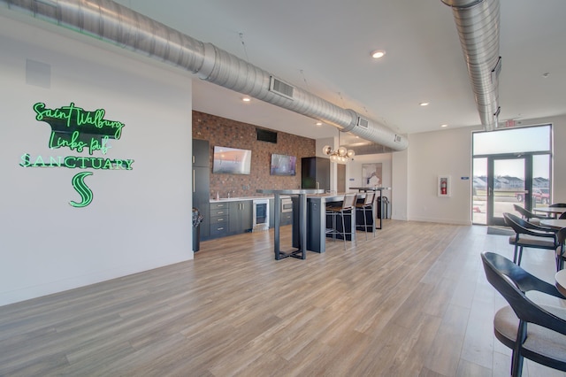 interior space featuring a chandelier, beverage cooler, and light wood-type flooring