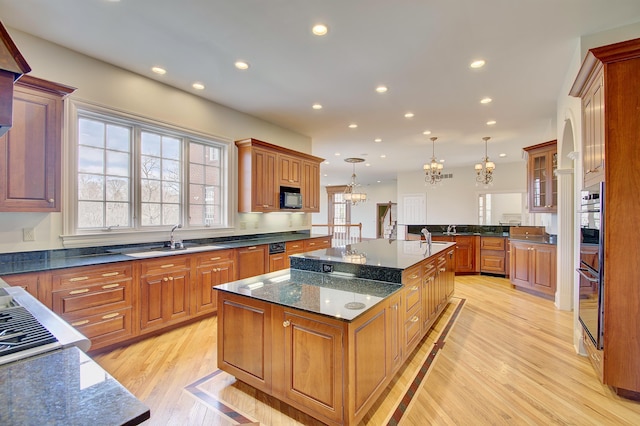 kitchen with recessed lighting, a large island with sink, black microwave, and light wood finished floors