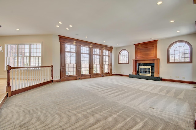 unfurnished living room with light carpet, recessed lighting, baseboards, and a high end fireplace