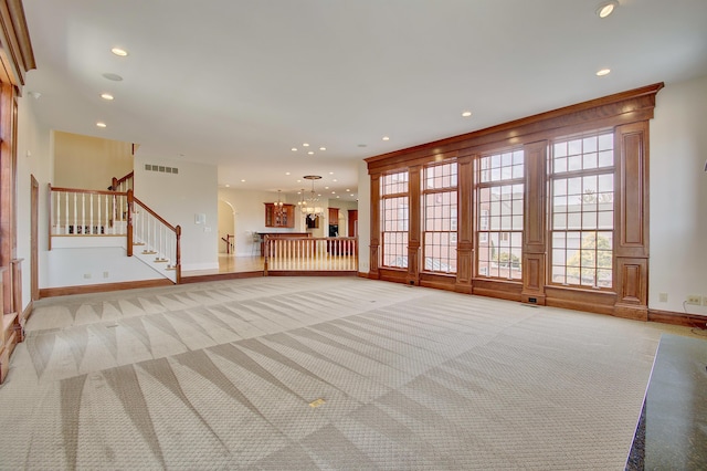 unfurnished living room with recessed lighting, visible vents, light colored carpet, and stairway