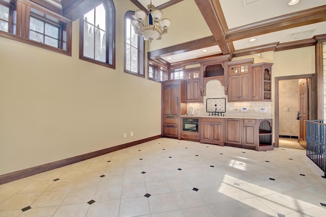 kitchen with baseboards, coffered ceiling, beam ceiling, a sink, and a notable chandelier