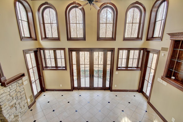 doorway with a high ceiling, light tile patterned floors, french doors, and baseboards