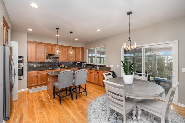 kitchen featuring decorative backsplash, hanging light fixtures, a center island, light hardwood / wood-style floors, and stainless steel appliances