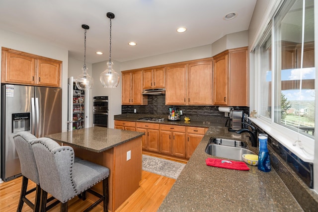 kitchen with pendant lighting, sink, a kitchen bar, a center island, and stainless steel appliances