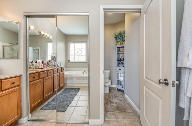 bathroom featuring vanity, tile patterned floors, a tub, and toilet