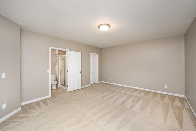 unfurnished bedroom featuring light colored carpet and ensuite bathroom