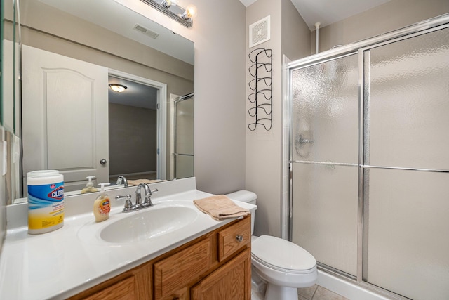 bathroom with a shower with door, vanity, tile patterned flooring, and toilet