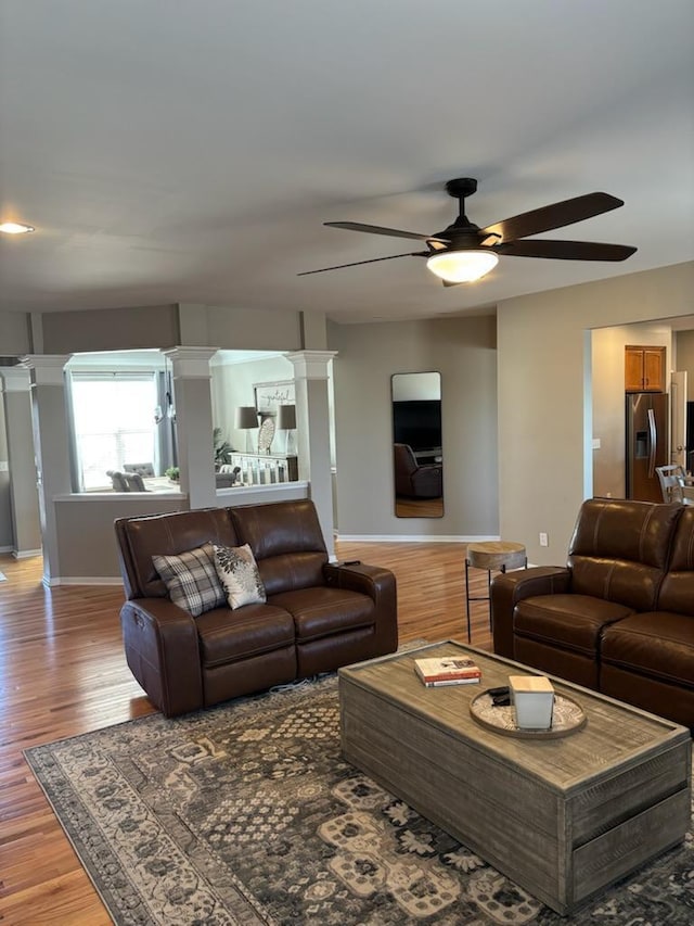 living room featuring decorative columns, hardwood / wood-style flooring, and ceiling fan