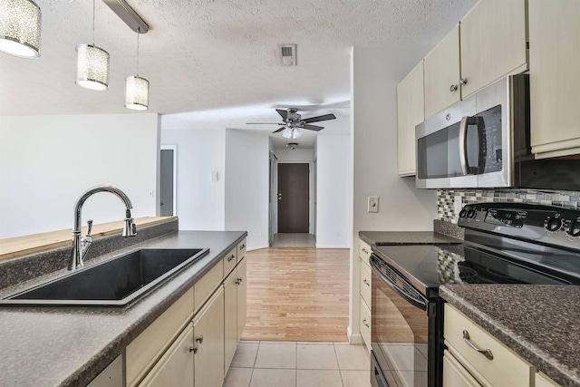 kitchen with decorative light fixtures, black range with electric stovetop, sink, and cream cabinets